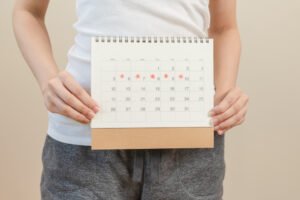 Woman looking concerned at a calendar, representing a late period.