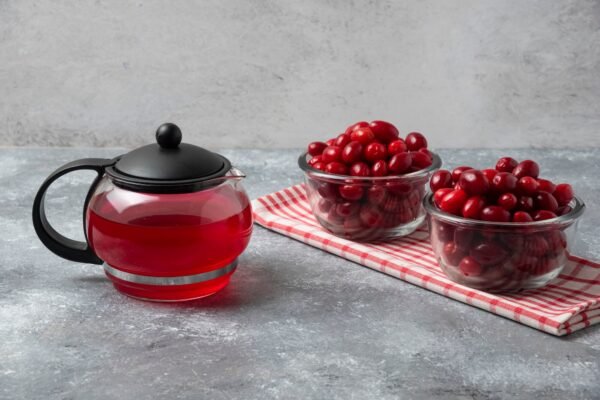 Glass of diluted cranberry juice next to toddler sippy cup on kitchen table